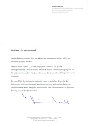 Das Bild zeigt das originale Grußschreiben von Arnim Laschet, dessen Text nebenan dargestellt wird.